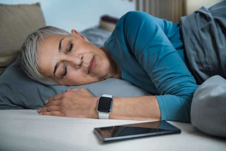 Woman sleeping with phone and watch nearby.