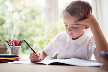 Boy writing in a notepad doing his school work or homework