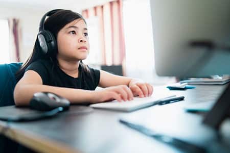 Young girl at home on computer doing home work.