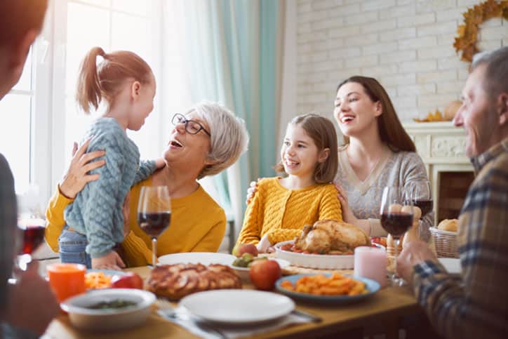 Happy Thanksgiving Day! Autumn feast. Family sitting at the table and celebrating holiday. Grandparents, mother, father and children. Traditional dinner.